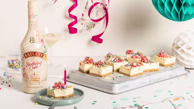 Funfetti Cheesecake Bites on tray with bottle baileys birthday cake