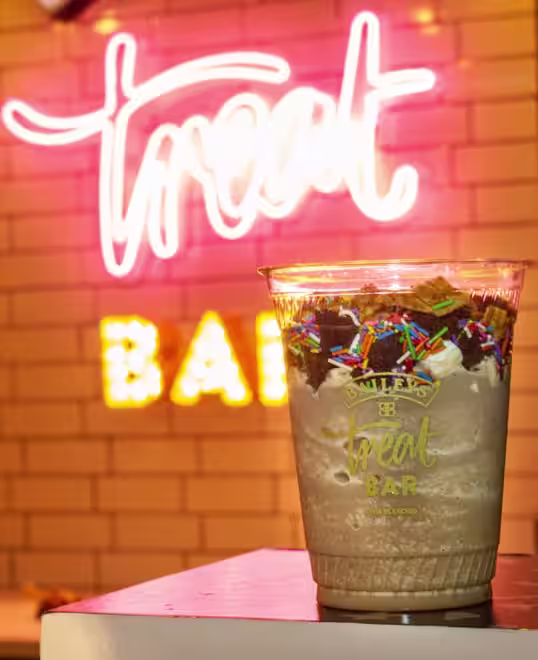 A Baileys iced coffee with the Baileys Treat Bars behind